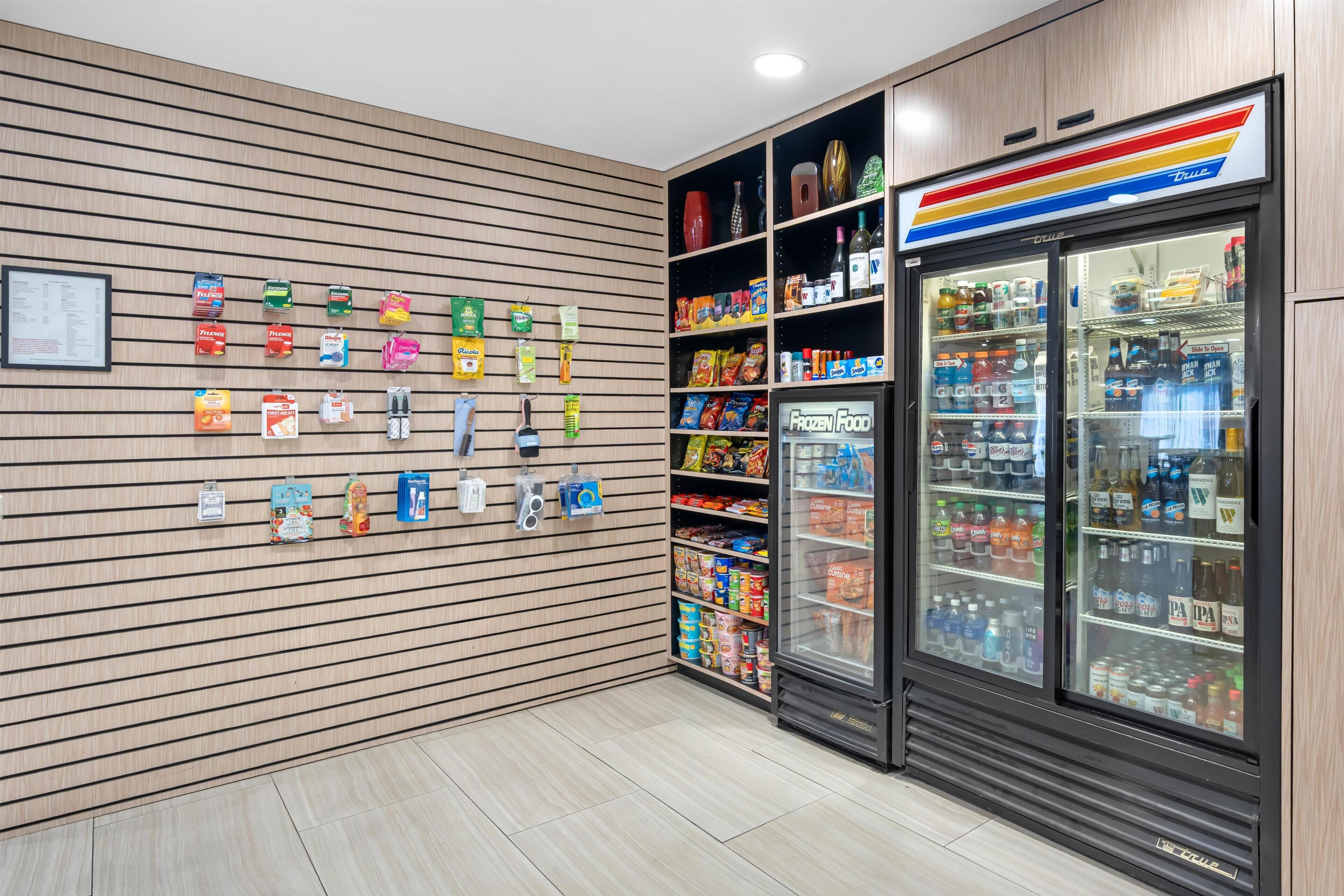 Un espace de vente propre et moderne, avec une variété de produits emballés présentés sur des étagères et un rayon réfrigéré contenant des boissons.