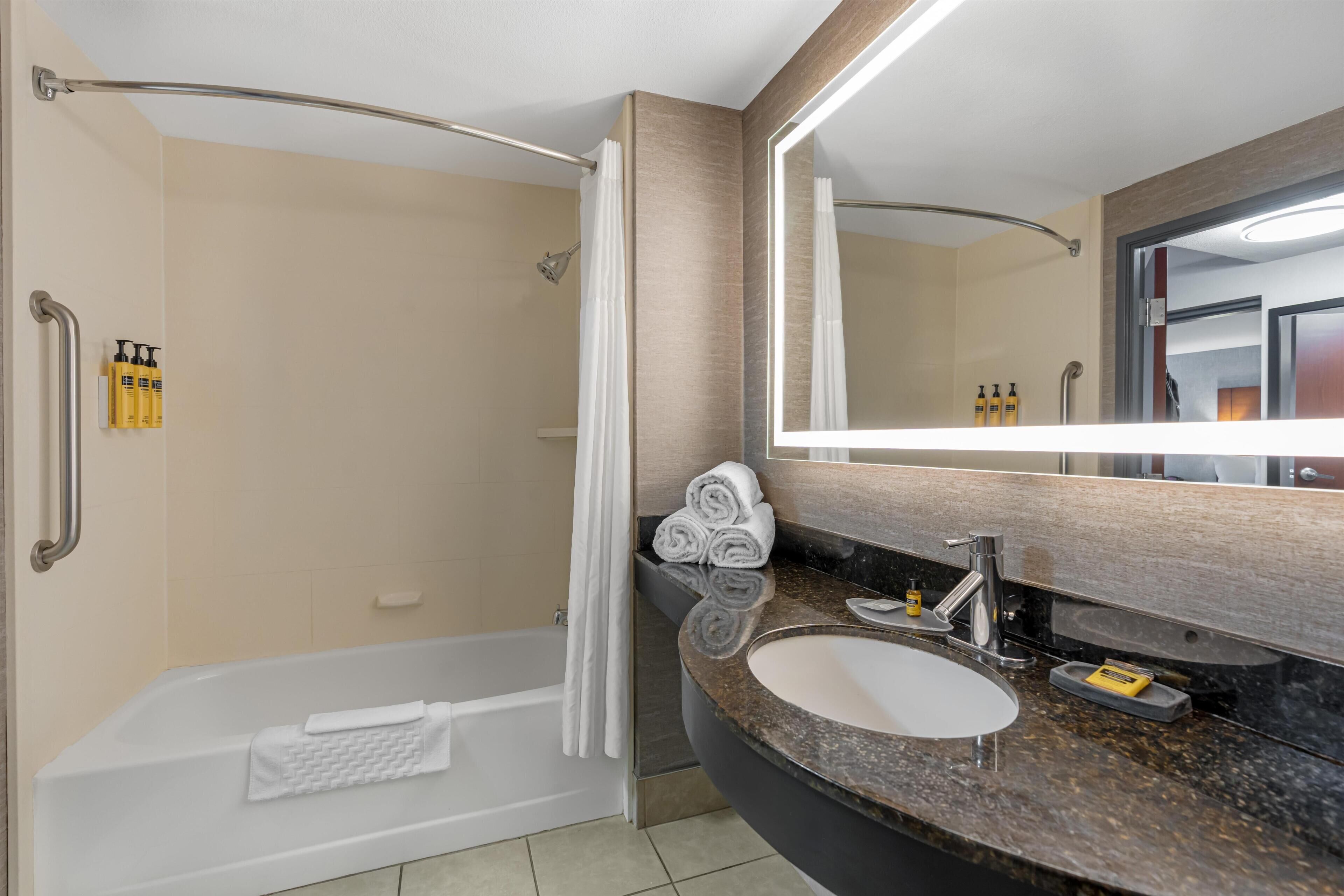 A modern bathroom with a bathtub, a sink, and a large mirror.