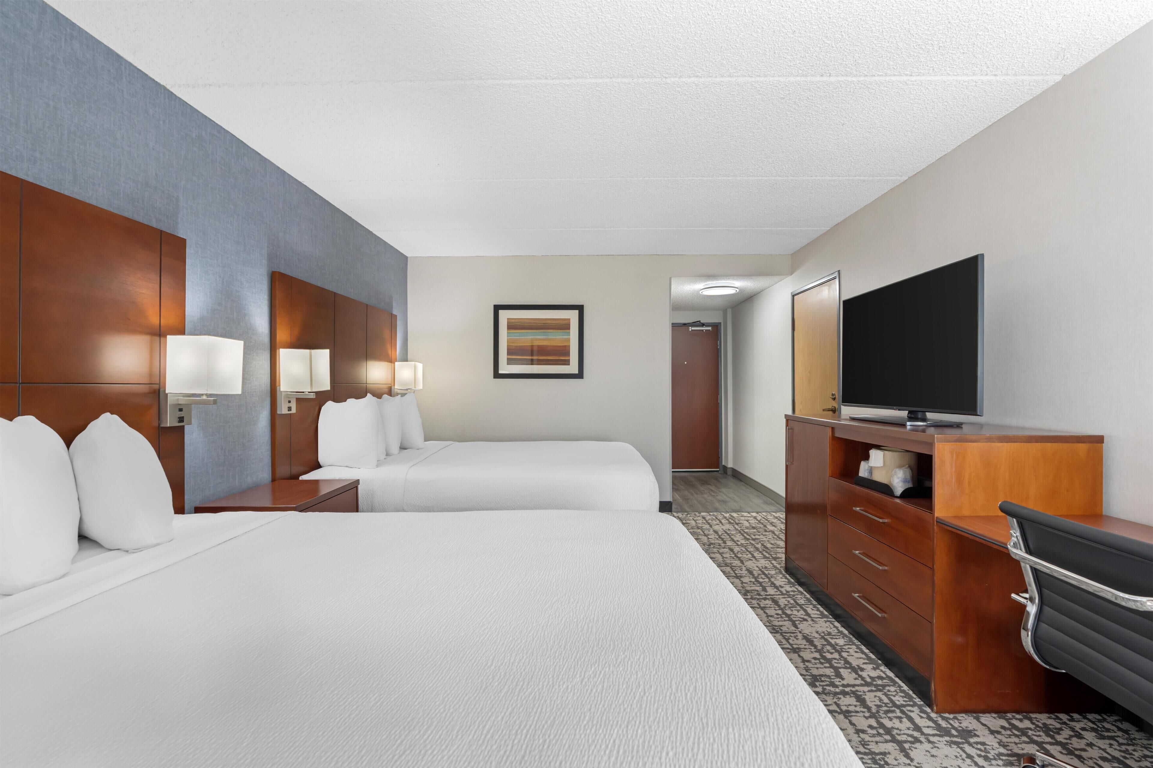 Una habitación de hotel con dos camas, televisión, escritorio y cómoda.