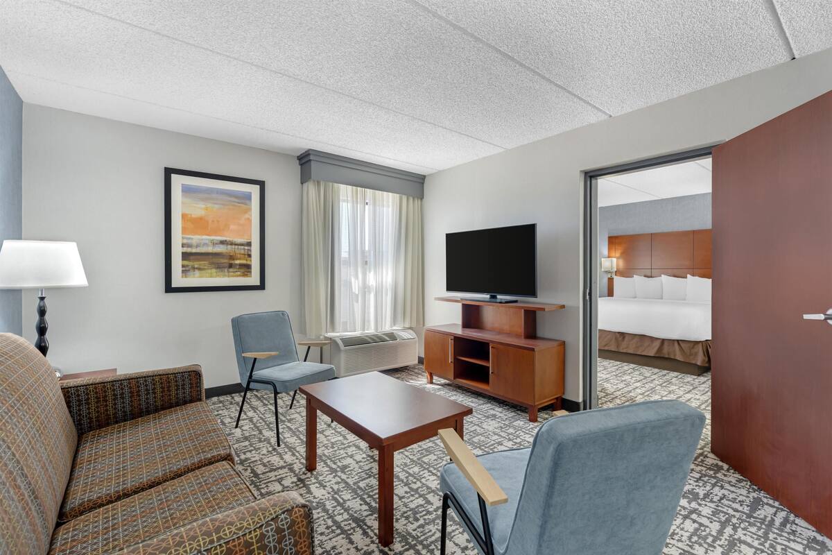 Une chambre d’hôtel avec un canapé, un fauteuil, une télévision et un lit.