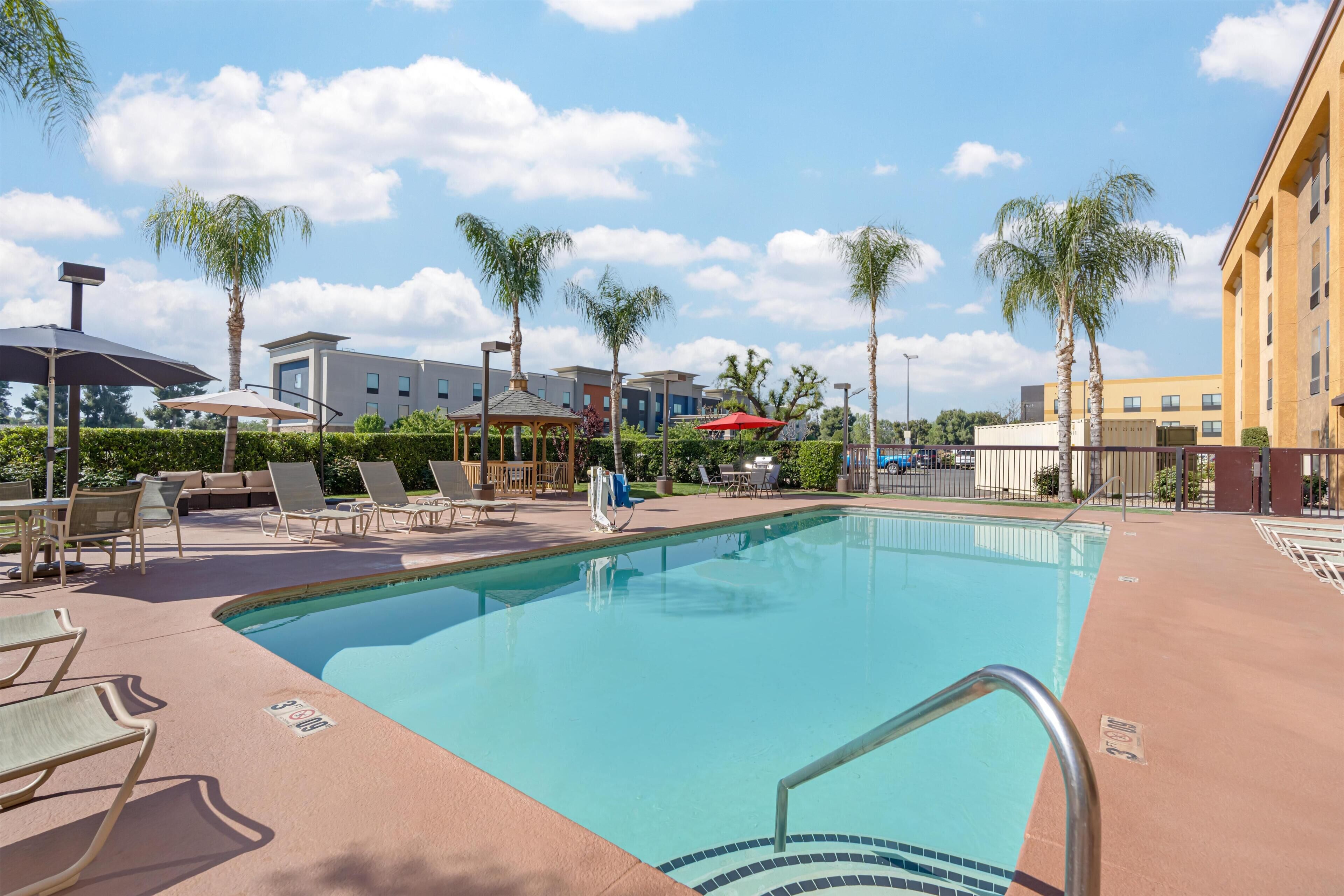 Een buitenzwembad, ligstoelen bij het zwembad