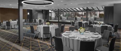 A conference room with round tables, grey chairs, and white tablecloths.