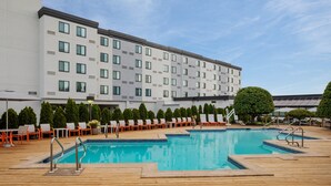 Un espace piscine d’hôtel comprenant une grande piscine, des chaises longues et un bâtiment doté de nombreuses fenêtres.