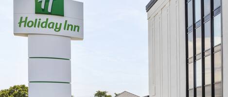 Señal de Holiday Inn con un edificio moderno al fondo.