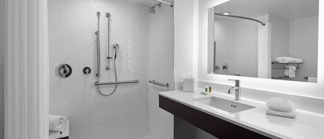 A modern bathroom with a shower, a sink, and a mirror.