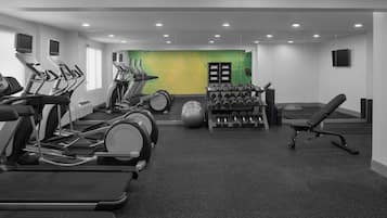 Un gimnasio con cintas de correr, una máquina de remo, mancuernas y un banco.