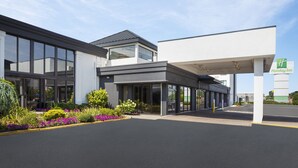 Un hôtel Holiday Inn au design moderne, doté de grandes fenêtres, d’une entrée couverte et de jardins aménagés.