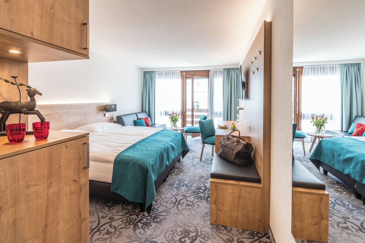 A hotel room with a bed, two bedside tables, a desk, a chair, and a sofa.