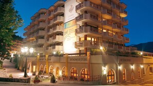 Un hotel de varios pisos con balcones, un letrero central y un restaurante.
