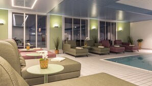 Zona de piscina interior moderna con asientos e iluminación ambiental.