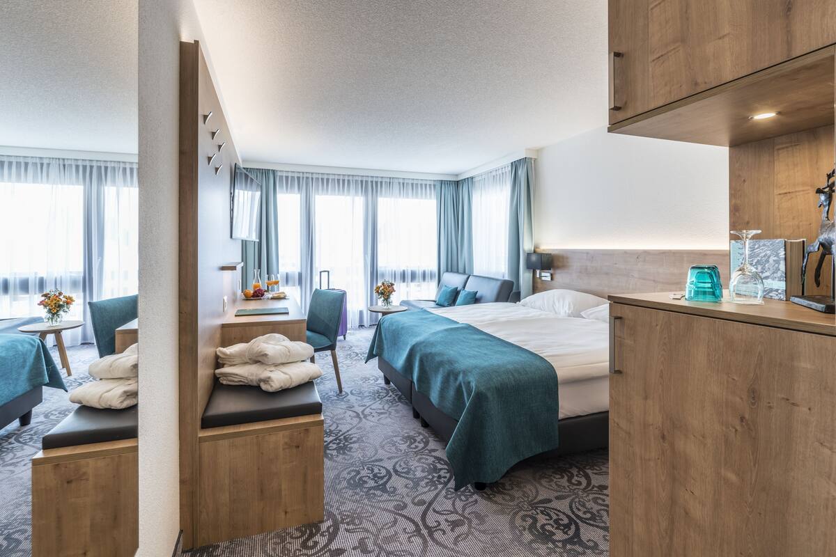 A hotel room with a large bed, two bedside tables, a desk, and a chair.