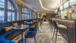 Un área de lounge moderna con bar, asientos y ventanas amplias.