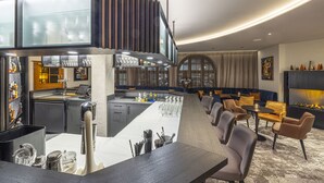 Un moderno vestíbulo de hotel con una zona de bar, asientos y una chimenea.