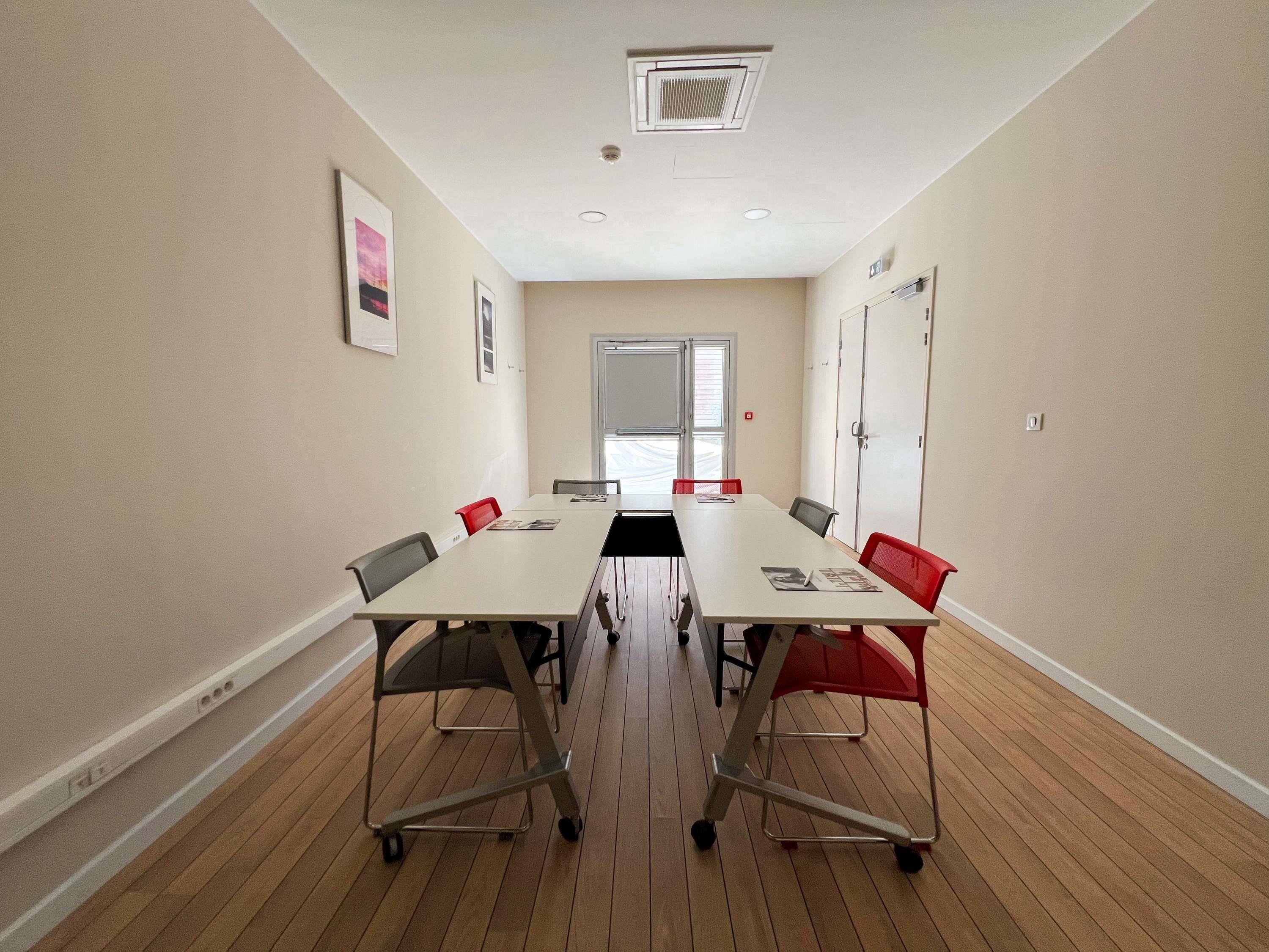 A conference room with a long table, chairs, and a door.
