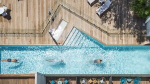 Piscina en la azotea con sillas de descanso y barandilla de cristal.