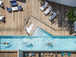 Piscina en la azotea con sillas de descanso y barandilla de cristal.