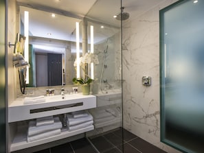 A modern bathroom with a glass-enclosed shower, a vanity with a mirror, and a potted orchid.