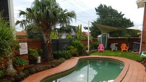 A backyard with a swimming pool, brick pathway, and a sign prohibiting diving. - Werribee Motel & Apartments (Werribee)