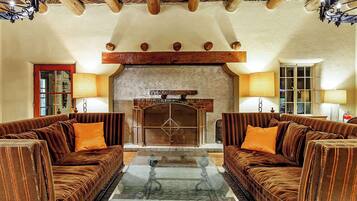 A cozy living room with two plush sofas, a glass coffee table, and a fireplace.
