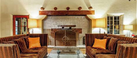 A cozy living room with two plush sofas, a glass coffee table, and a fireplace.