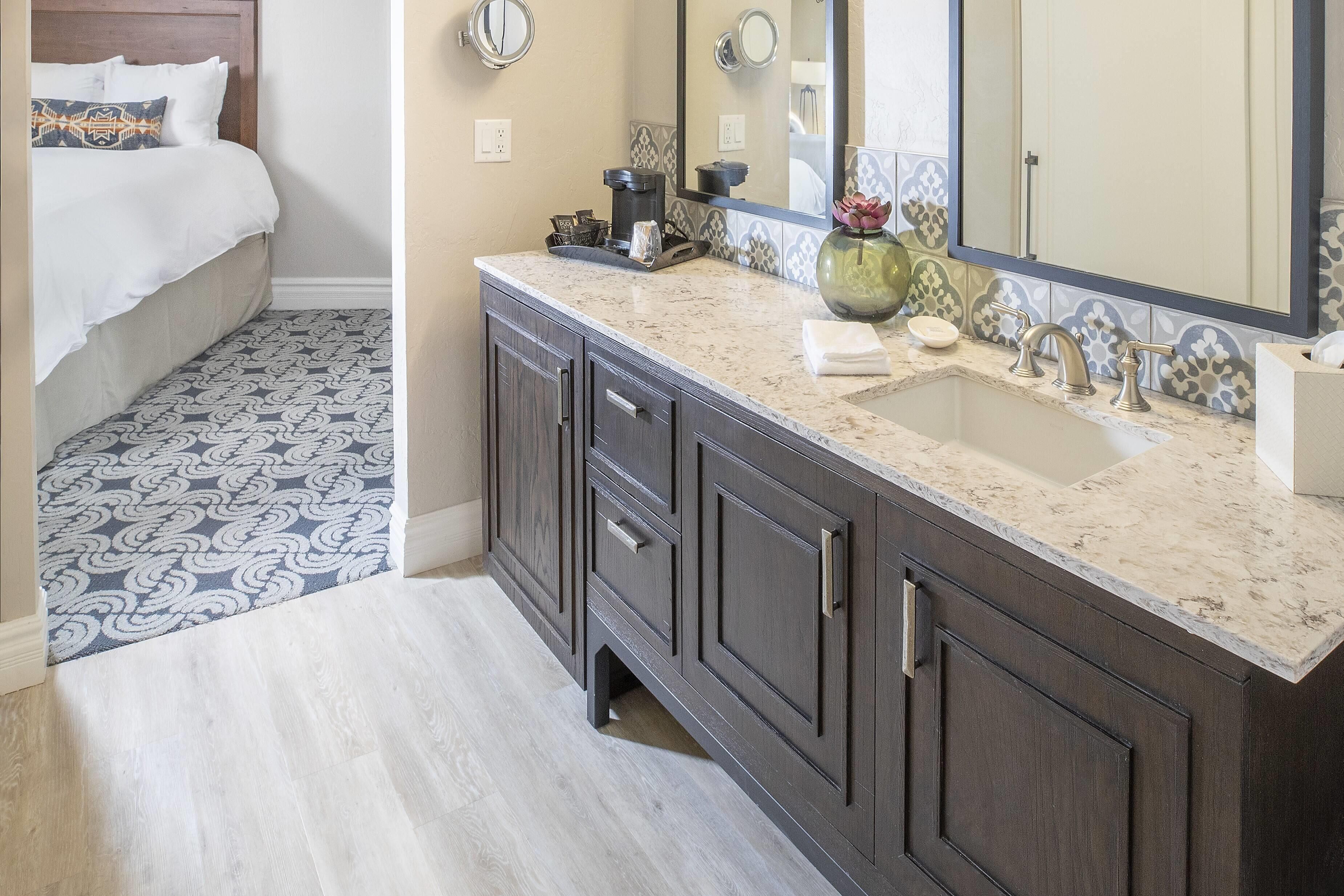 Une salle de bain avec un lavabo, un miroir et des meubles de rangement sombres.