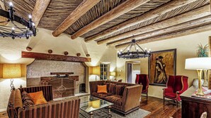 A rustic interior with a wooden ceiling, a fireplace, and a seating area with a glass coffee table. - Westward Look Wyndham Grand Resort and Spa (Tucson)