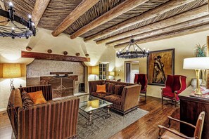 A rustic interior with a wooden ceiling, a fireplace, and a seating area with a glass coffee table.