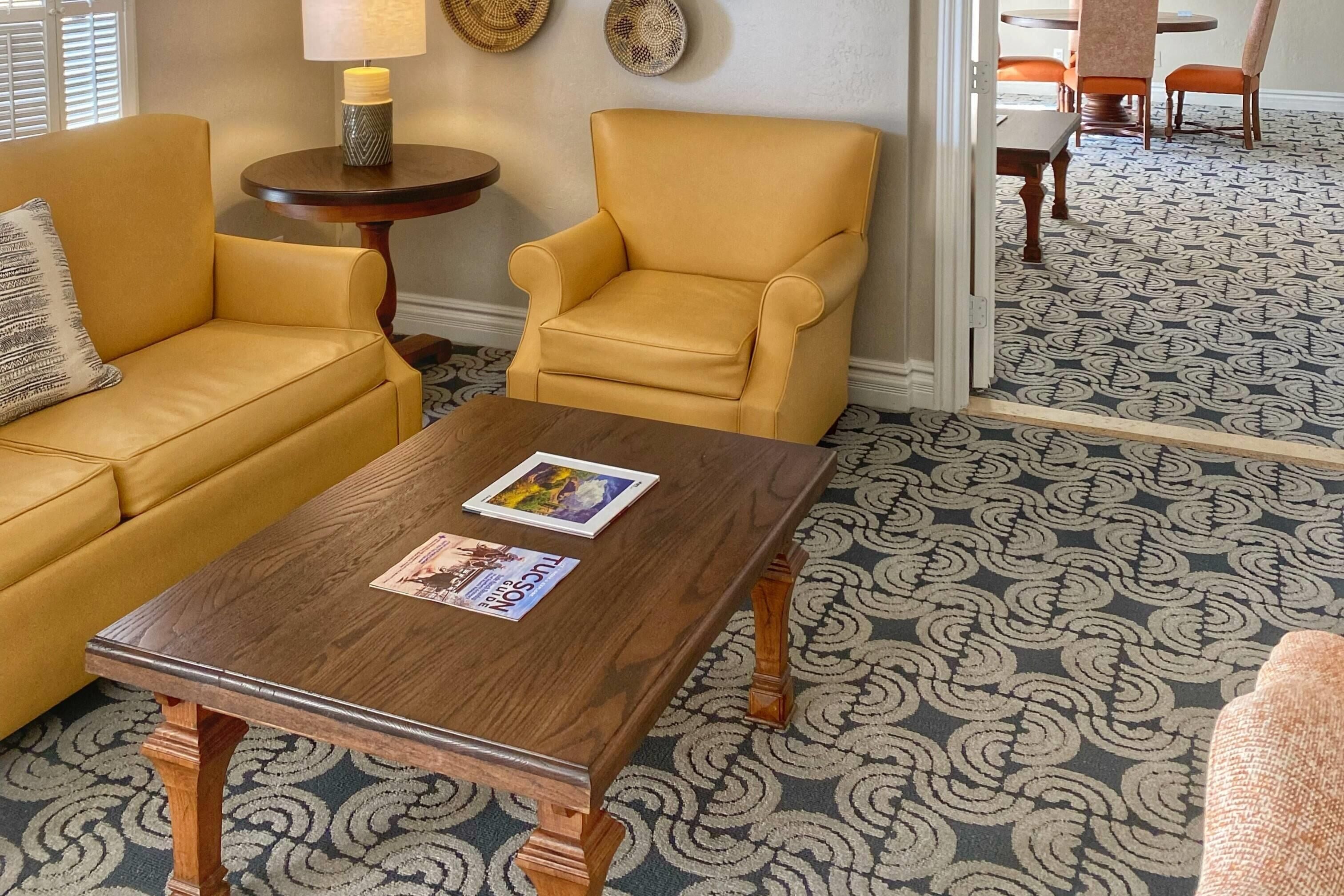 A living room with a sofa, armchair, coffee table, and a patterned carpet.