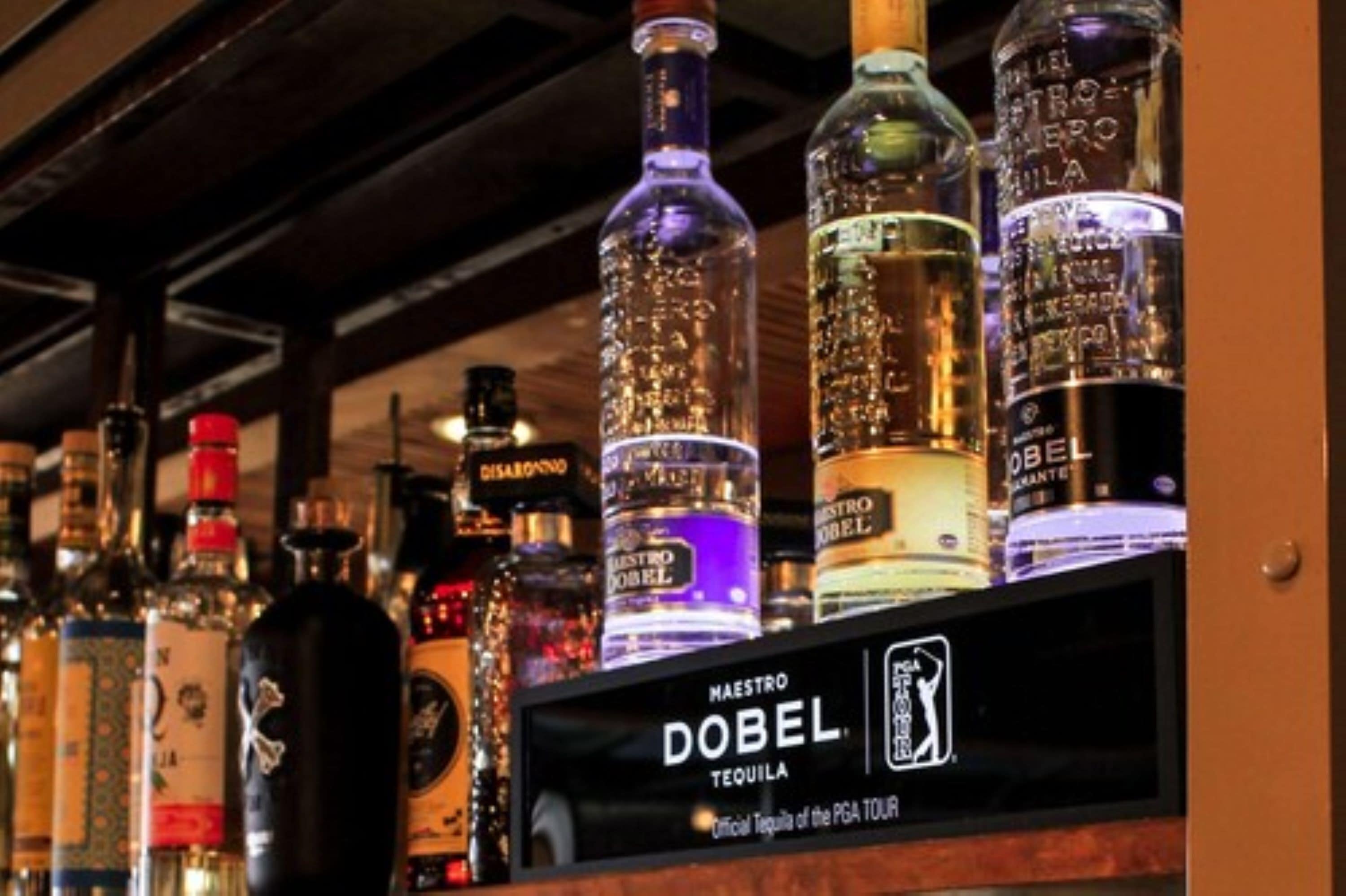A bar with various liquor bottles, including Maestro Dobel Tequila prominently displayed.