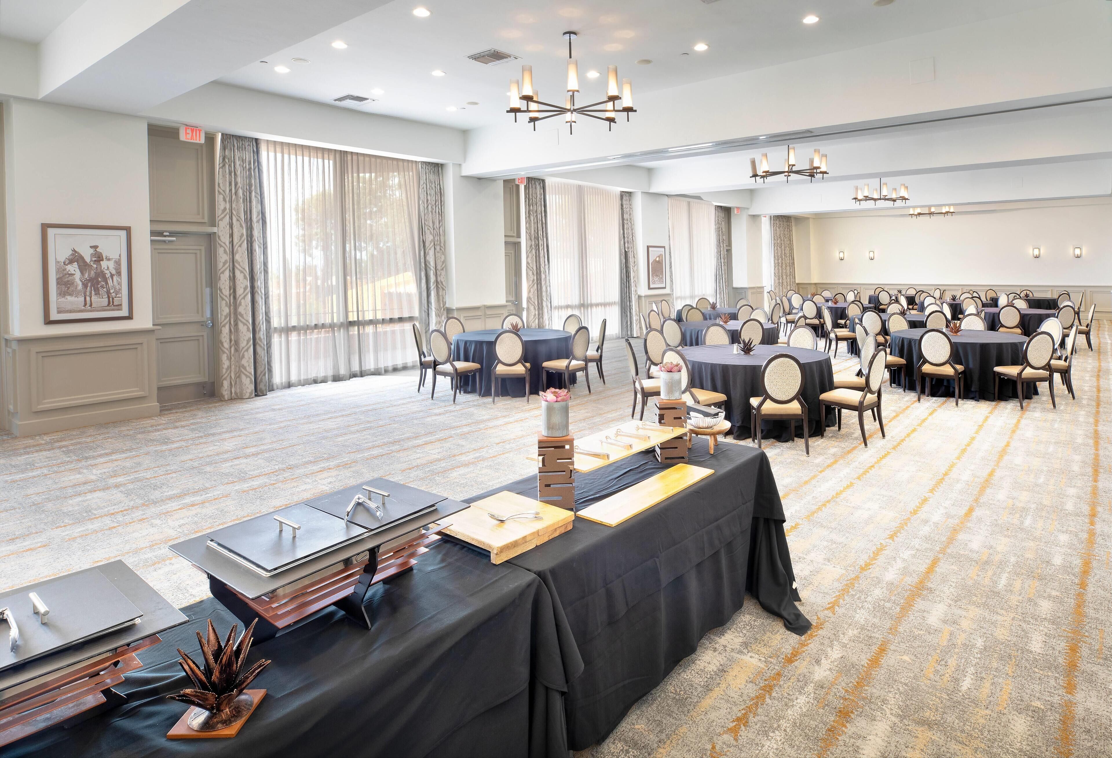 A spacious conference room with multiple tables, chairs, and a carpeted floor.