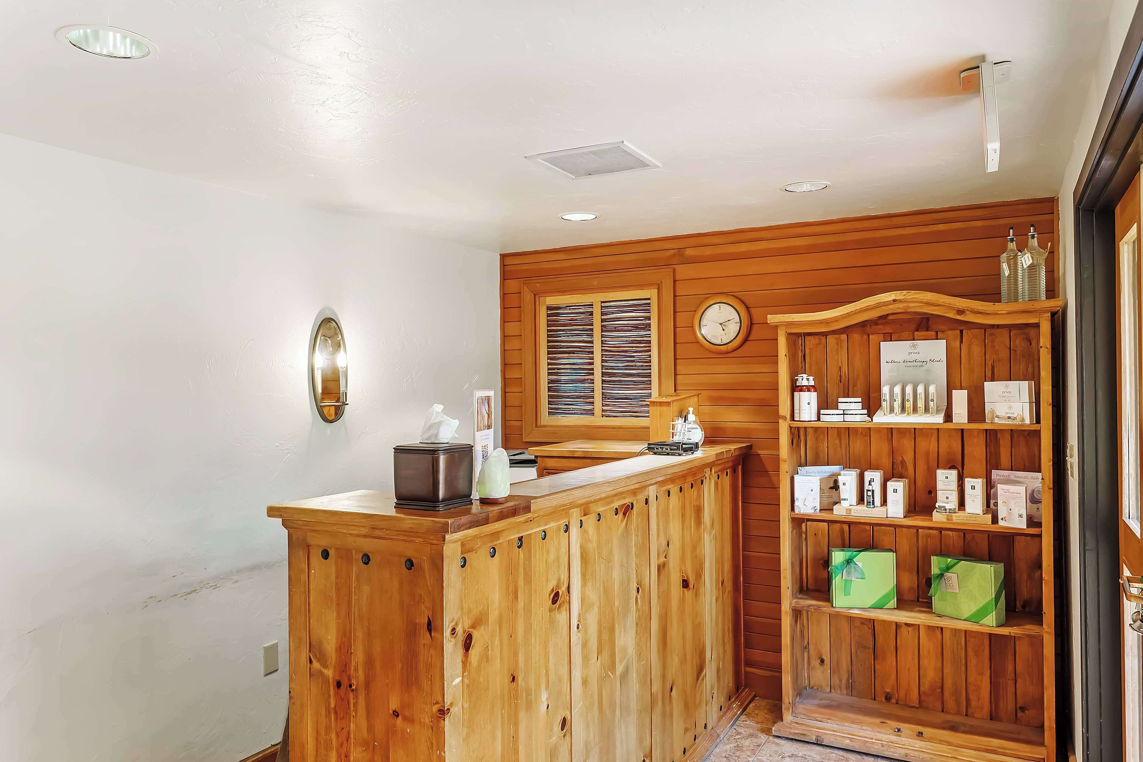 A wooden reception desk with a clock and a window with blinds.