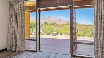 A hotel room with a large sliding glass door leading to an outdoor patio with a mountain view.