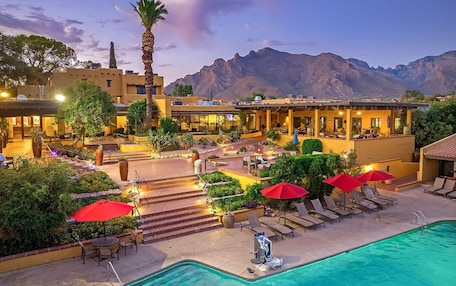 A resort with a swimming pool, outdoor seating, and mountain views.