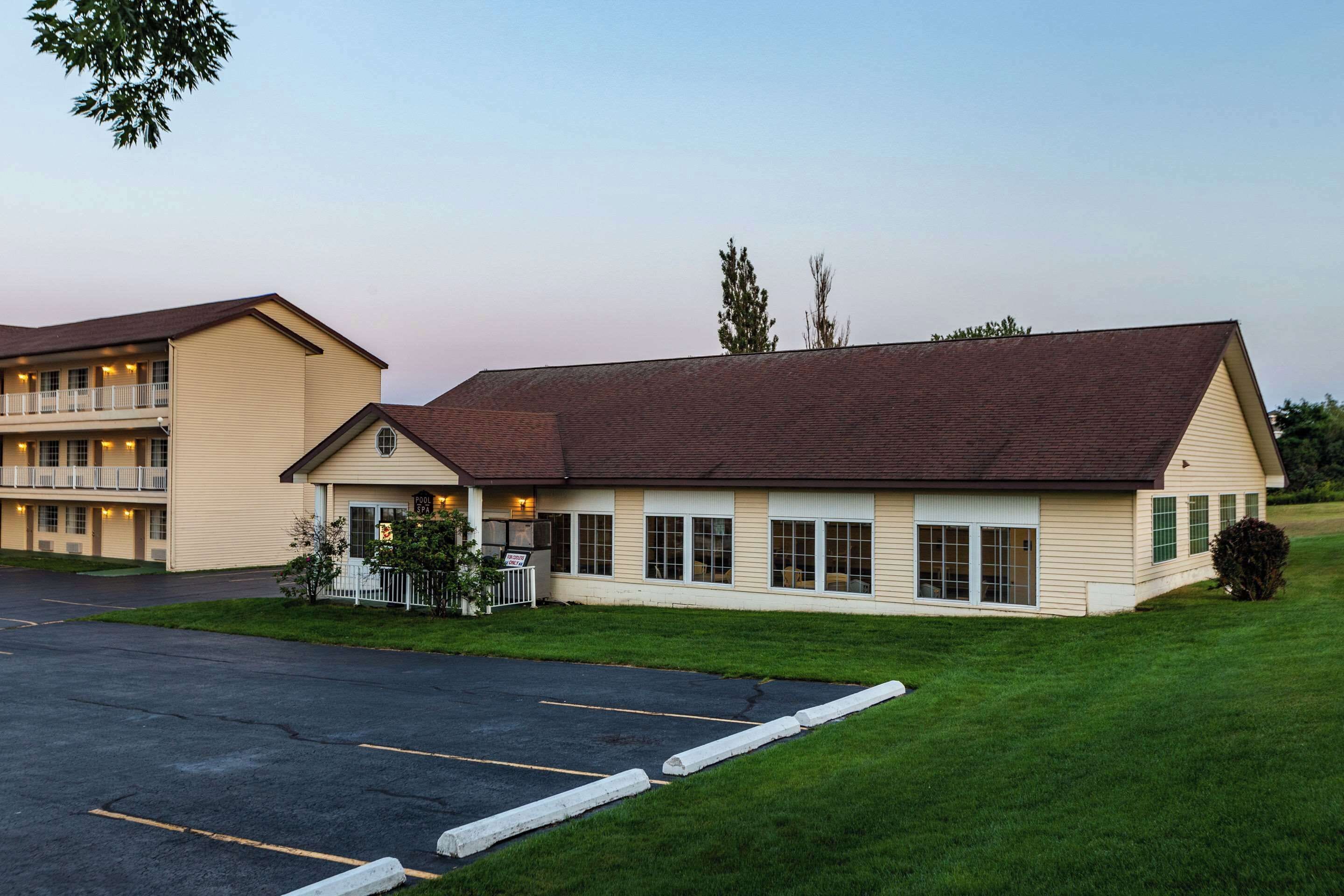 A two-story motel with a parking lot and a well-maintained lawn.