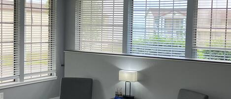 A room with two gray chairs, a small table with a lamp, and a ceiling fan.