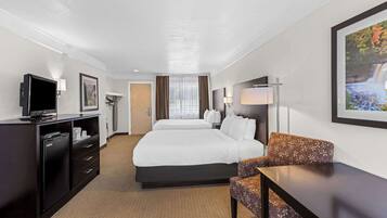 Habitación de hotel con una cama grande, un escritorio, una silla, un televisor y un cuadro en la pared.