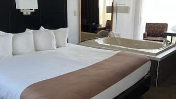 A large bed with a headboard, a bedside table, a mirror, a chair, and a view of the outdoors.