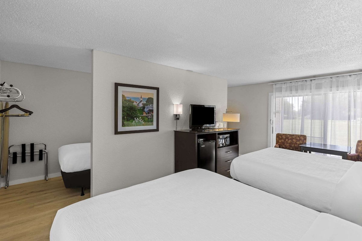 A hotel room with two beds, a TV, a desk, and a chair.