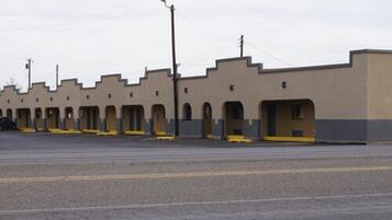 Une rangée de chambres de motel avec un toit plat, un parking et un ciel dégagé.