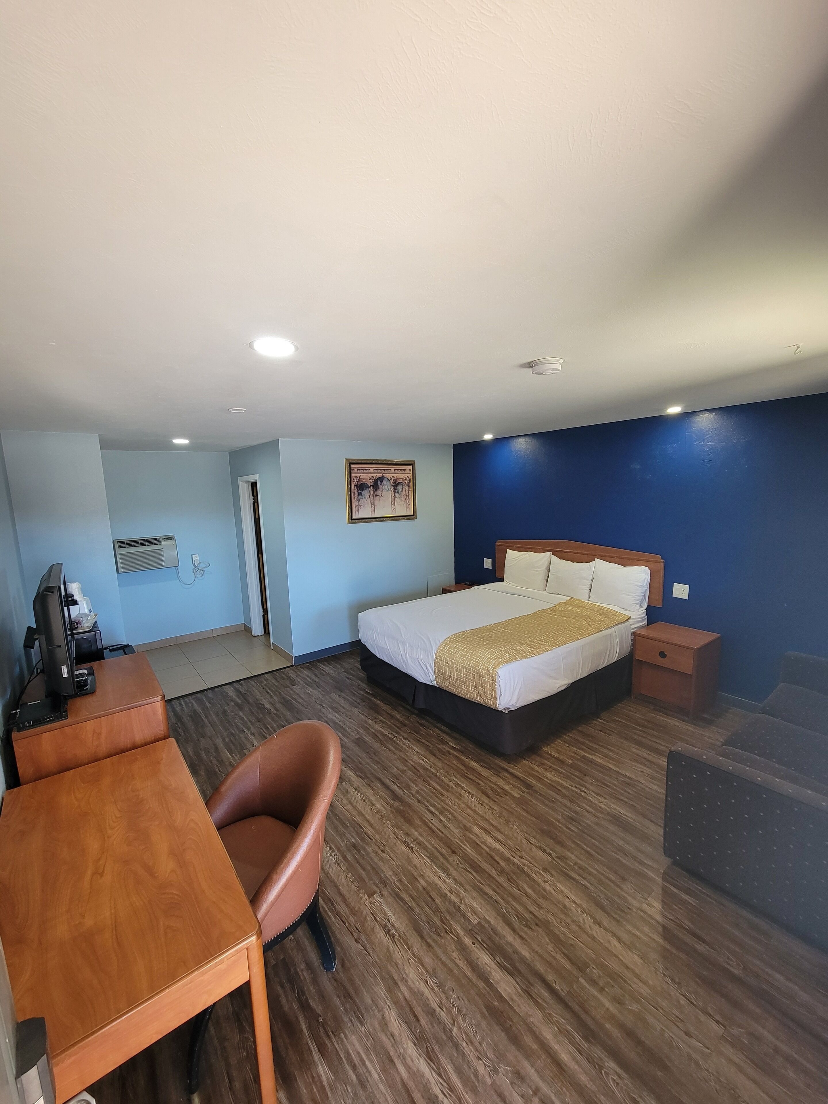 A hotel room with a bed, desk, chair, and a television.