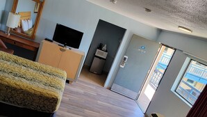 Une chambre d’hôtel équipée d’un lit, d’un bureau, d’une télévision, d’un four à micro-ondes et d’une porte donnant sur un balcon.