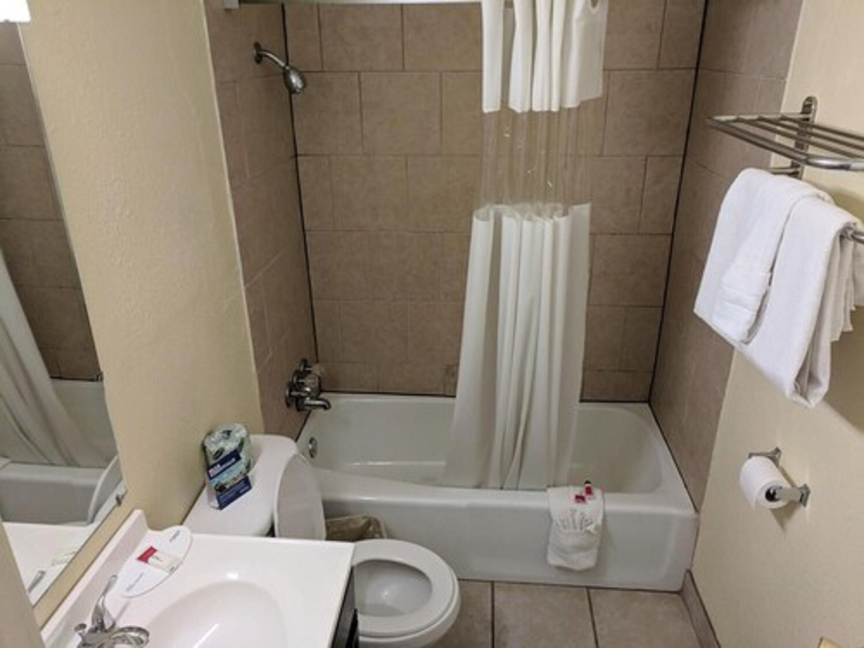 Un baño con bañera, inodoro, lavamanos y cortina de ducha.