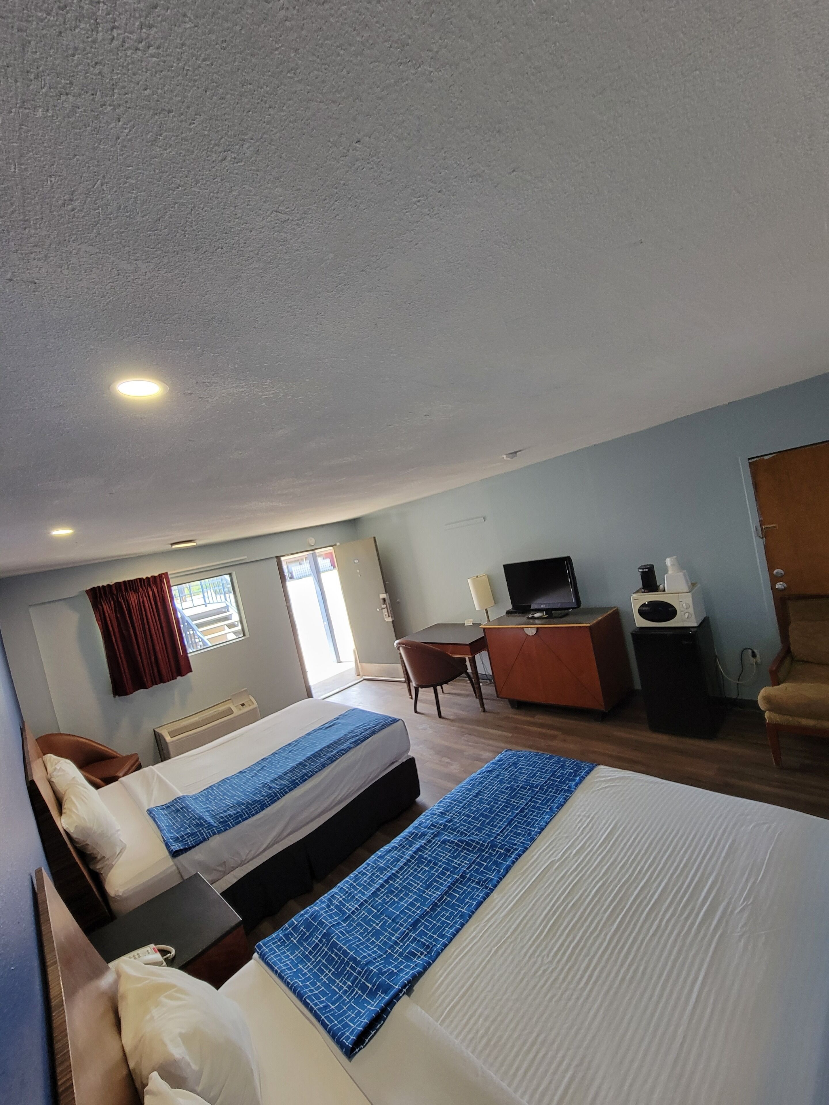 Une chambre d’hôtel avec deux lits, un bureau, une télévision et un four à micro-ondes.
