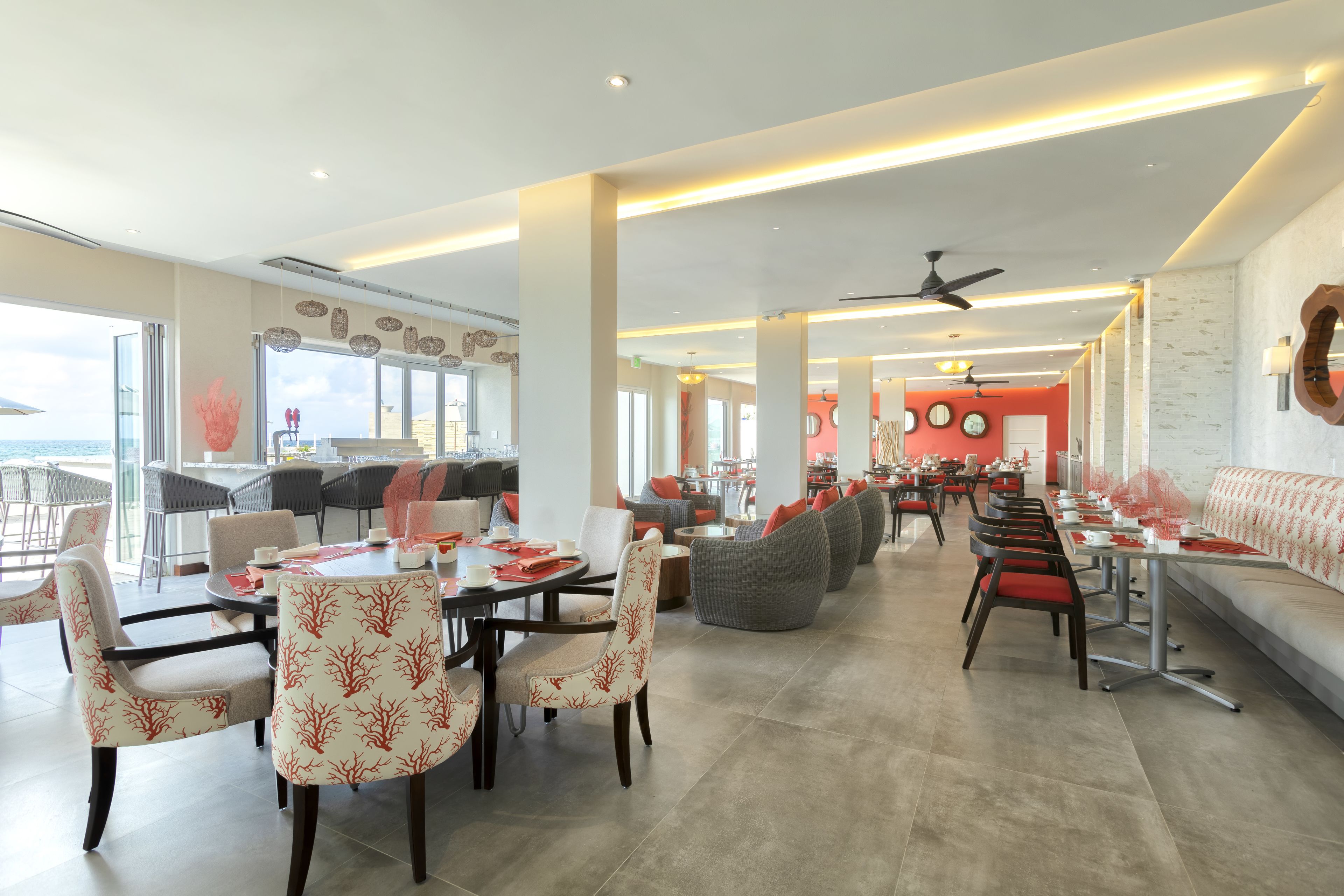 Un restaurante amplio con techos altos, iluminación moderna y una variedad de opciones de asientos, incluyendo mesas y sofás.