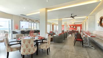 Un restaurante amplio con techos altos, iluminación moderna y una variedad de opciones de asientos, incluyendo mesas y sofás.
