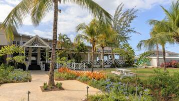 A resort with a covered walkway, palm trees, and a variety of flowering plants.
