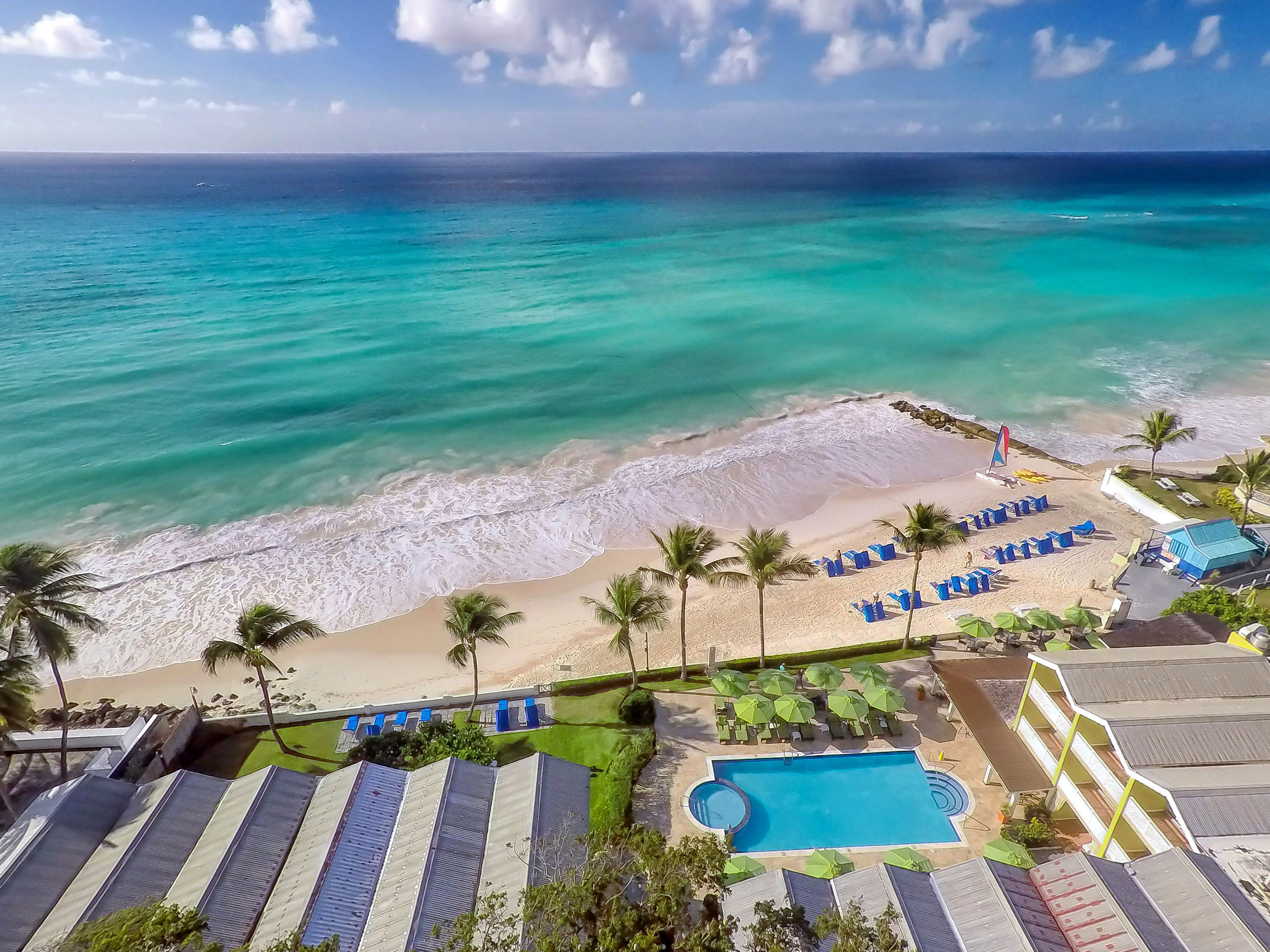 Un complexe hôtelier de bord de mer doté d’une piscine, de chaises longues et offrant une vue sur l’océan.