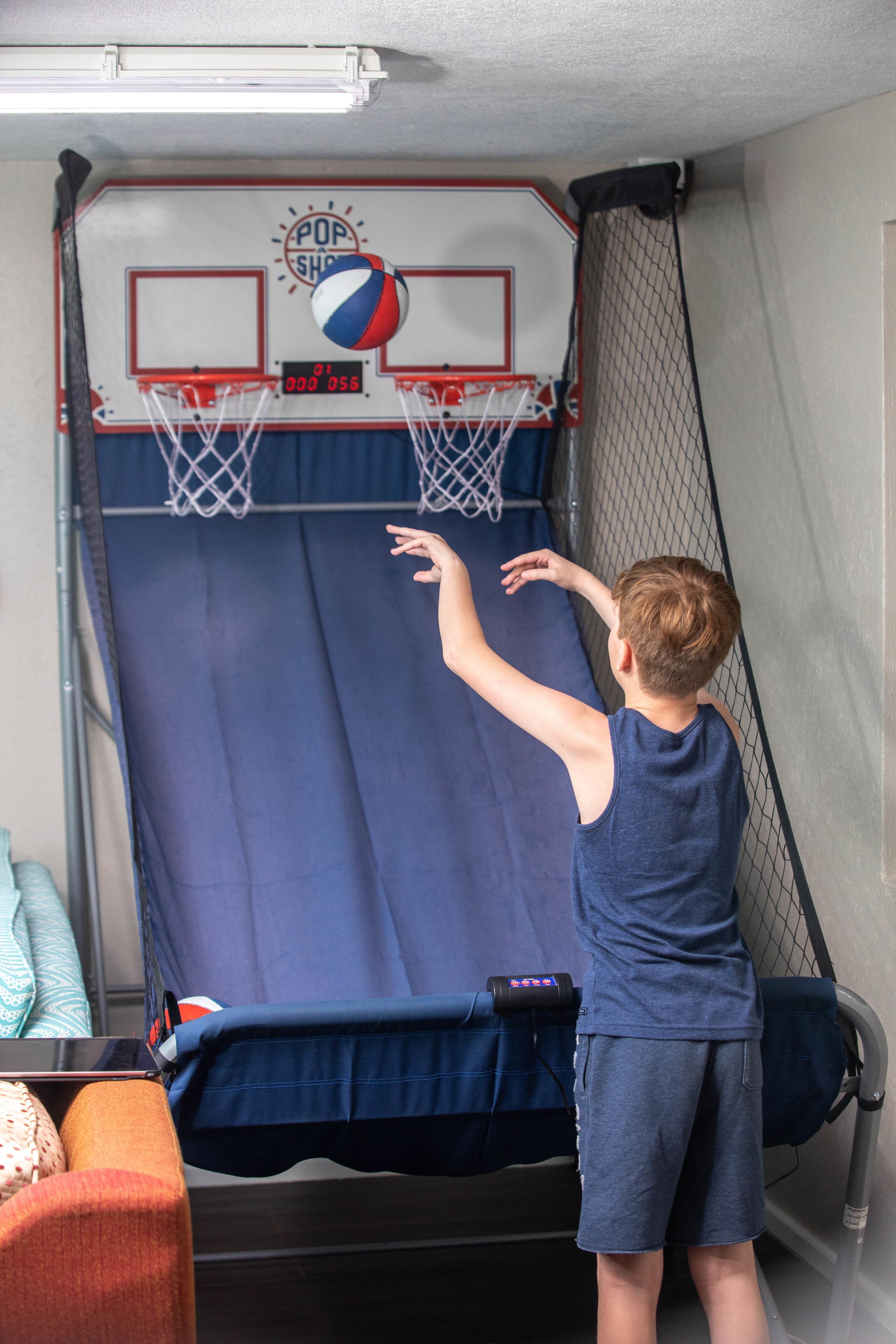 Un niño jugando al baloncesto en una cancha cubierta con aro y tablero.
