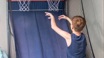 A child playing basketball in an indoor court with a hoop and backboard.