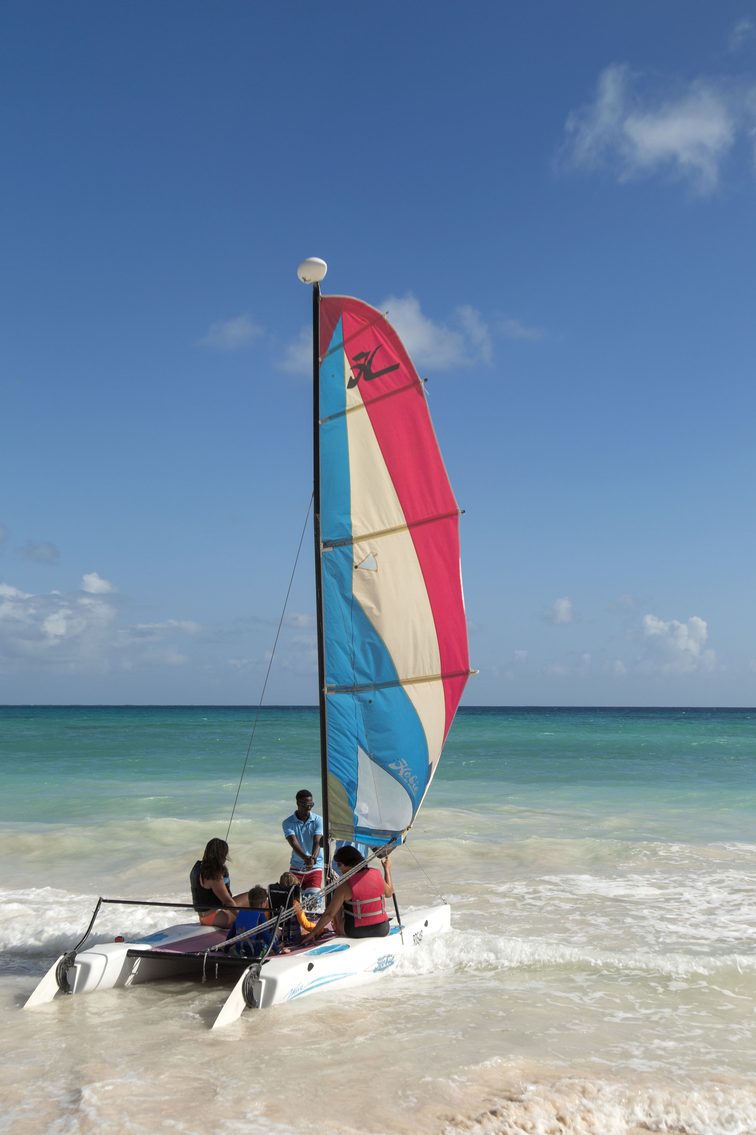 A sailboat with a colorful sail on a beach.